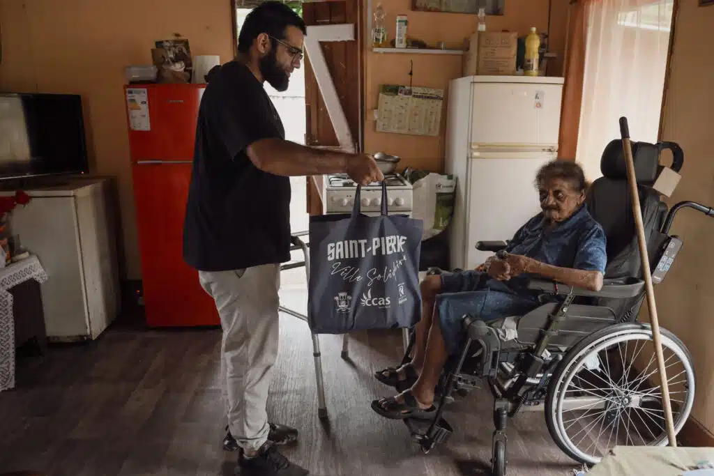 Abdou remet un panier alimentaire à madame Itema, bénéficaire de l'aide du CLAP.