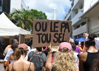 Une manifestante tient une pancarte sur laquelle on peut lire "Tu n'es pas toute seule" en créole.