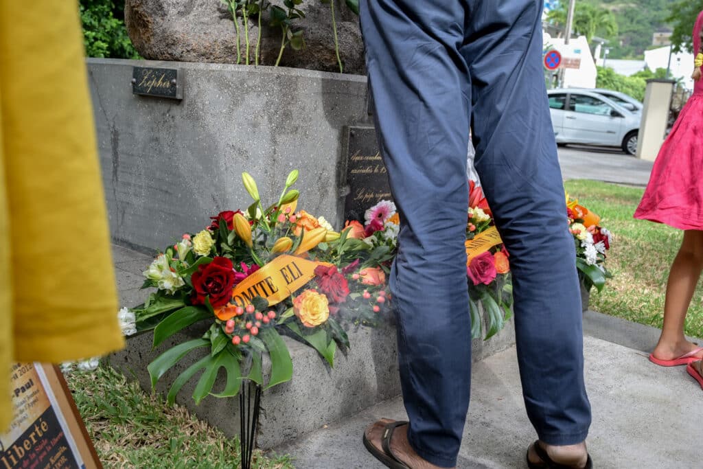 Gerbes de fleur déposées au pied de la statue commémorative.