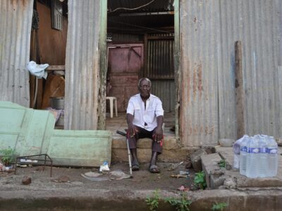 Un homme se tient devant sa maison ravagée par le passage de la tempête Dikeledi dans le Sud de Mayotte.