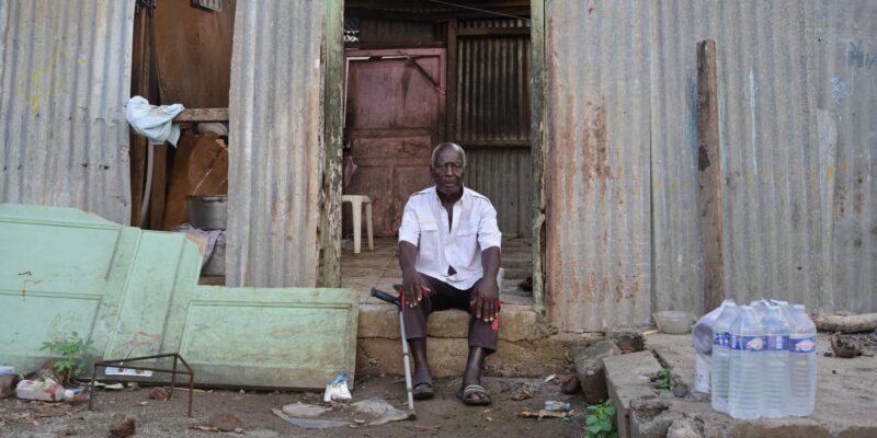 Un homme se tient devant sa maison ravagée par le passage de la tempête Dikeledi dans le Sud de Mayotte.