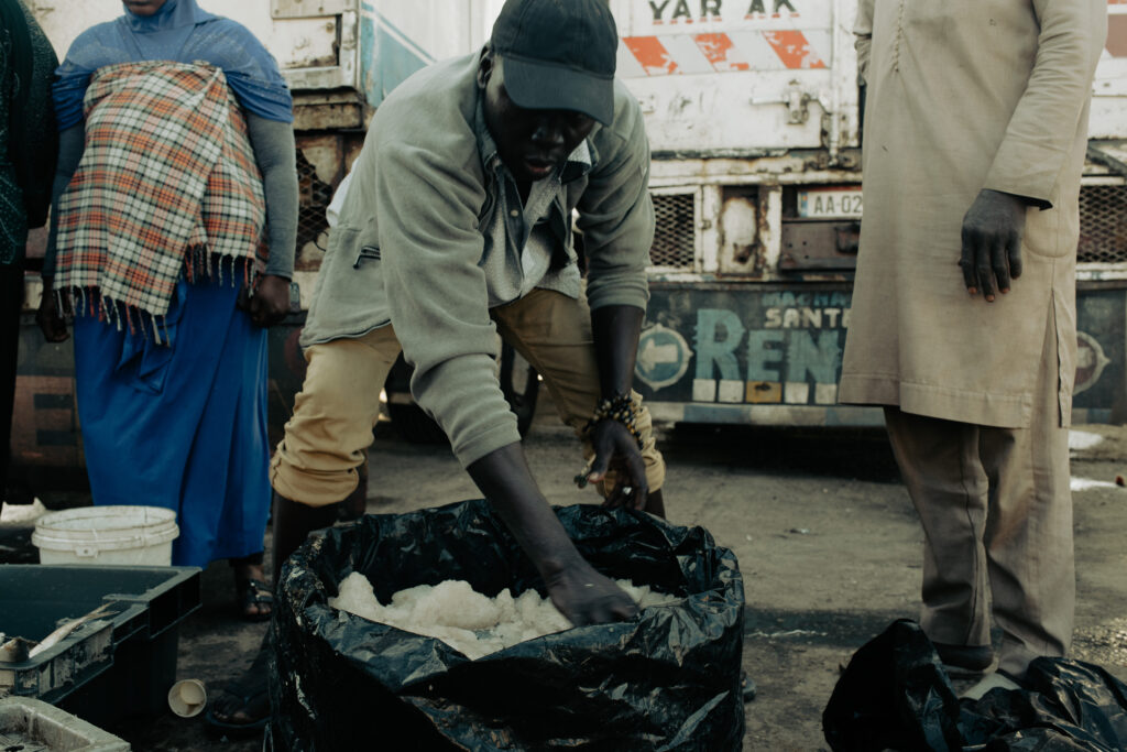 Un intermédiaire prépare une commande sur la place du marché. De plus en plus de personnes venus du Bénin, de Gambie et du Mali viennent travailler pour les transporteurs.
